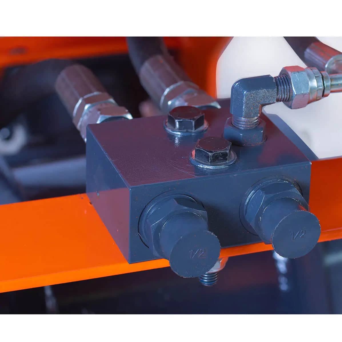 Hydraulic Manifold Block on Orange Frame - ExcavatorPin Close-up of a hydraulic manifold block with bolts and metal fittings mounted on an orange frame.